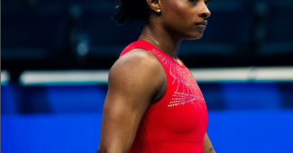Simone Biles, wearing a red leotard, walks on the podium at U.S. Olympic Trials.